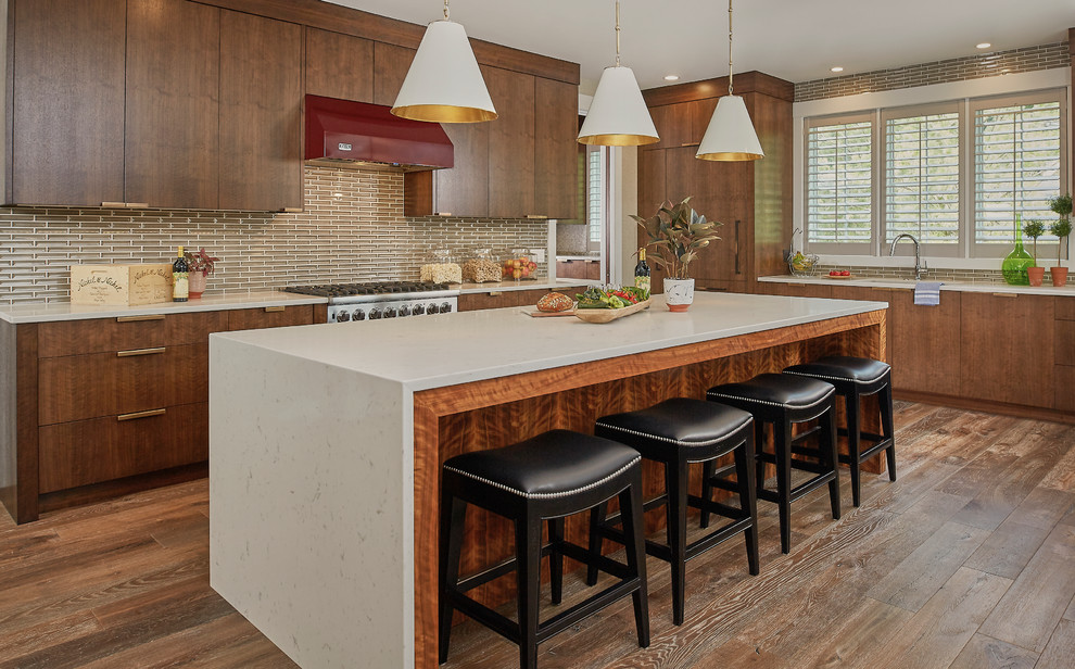 Large transitional l-shaped open plan kitchen in Grand Rapids with flat-panel cabinets, dark wood cabinets, granite benchtops, brown splashback, subway tile splashback, stainless steel appliances, dark hardwood floors, with island and an undermount sink.