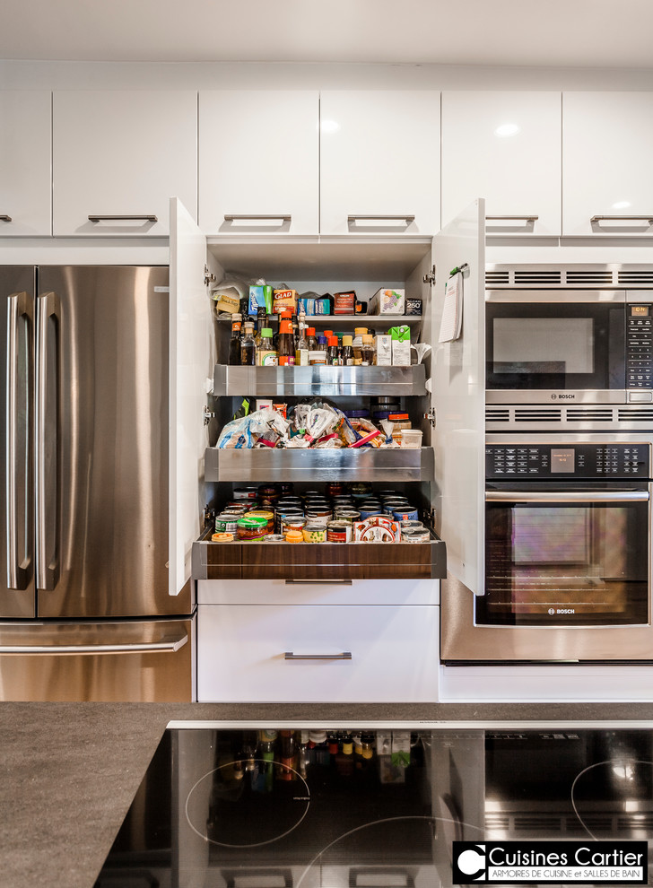 Inspiration for a large transitional galley medium tone wood floor eat-in kitchen remodel in Montreal with an undermount sink, flat-panel cabinets, dark wood cabinets, quartzite countertops, white backsplash, mosaic tile backsplash, stainless steel appliances and an island