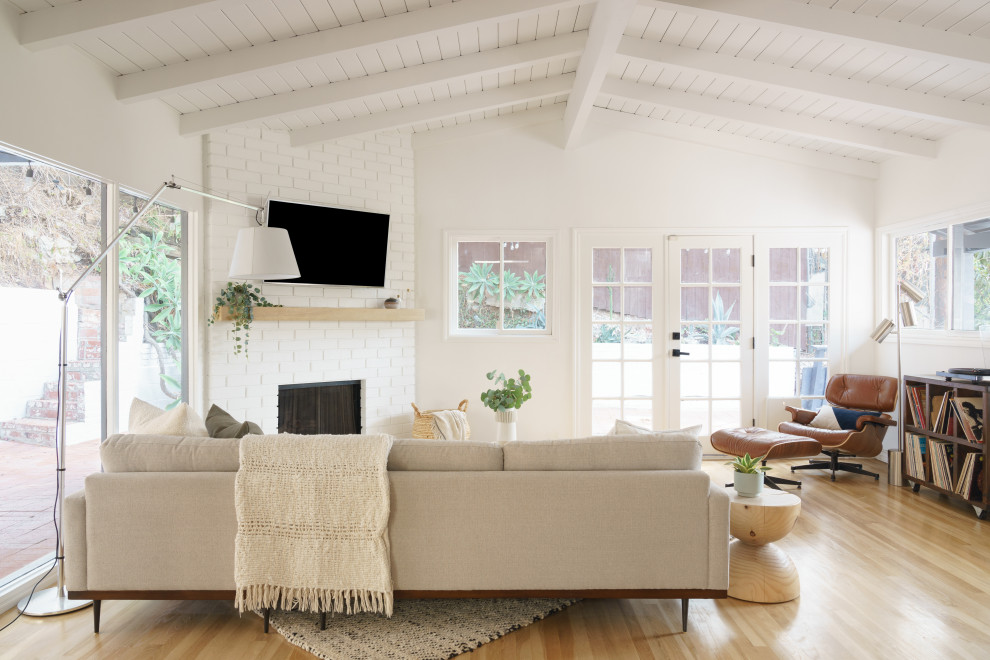 Inspiration for a small midcentury open concept living room in Los Angeles with white walls, medium hardwood floors, a corner fireplace, a brick fireplace surround, a corner tv, brown floor and timber.