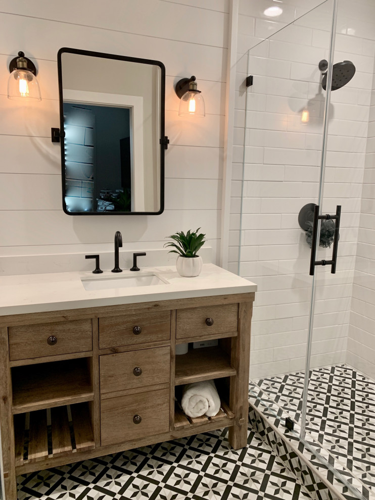 Photo of a country bathroom in Orange County with furniture-like cabinets, light wood cabinets, white tile, subway tile, white walls, cement tiles, solid surface benchtops, a hinged shower door and white benchtops.