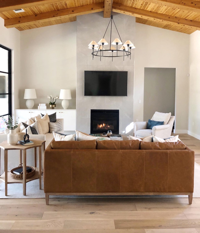 Transitional open concept living room in Austin with beige walls, medium hardwood floors, a standard fireplace, a wall-mounted tv and brown floor.