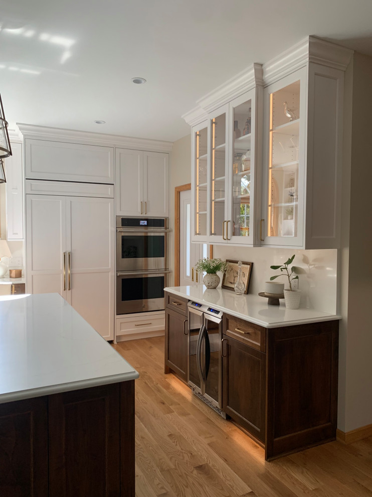 Inspiration for a light wood floor kitchen remodel with a double-bowl sink, shaker cabinets, white cabinets, quartz countertops, quartz backsplash, paneled appliances and an island