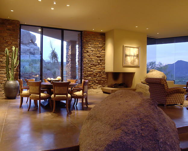 Photo of an open concept living room in Phoenix with beige walls, concrete floors, a corner fireplace, a stone fireplace surround, a built-in media wall and grey floor.