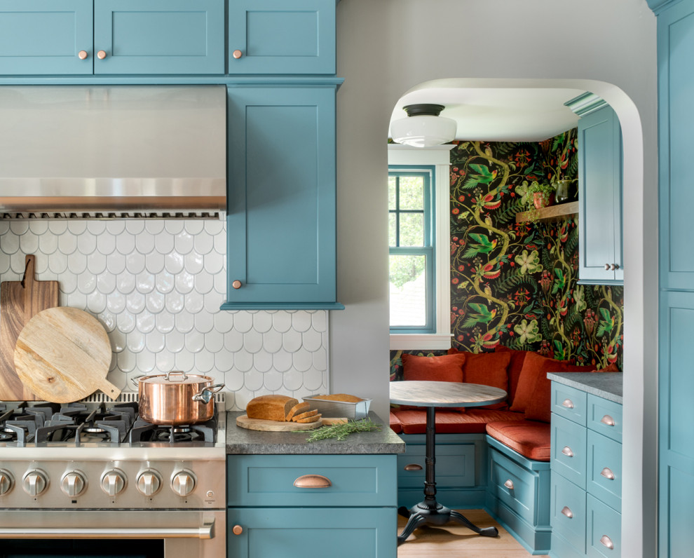 Design ideas for a mid-sized eclectic single-wall eat-in kitchen in Philadelphia with an undermount sink, shaker cabinets, blue cabinets, granite benchtops, white splashback, ceramic splashback, stainless steel appliances, light hardwood floors, with island, orange floor and grey benchtop.