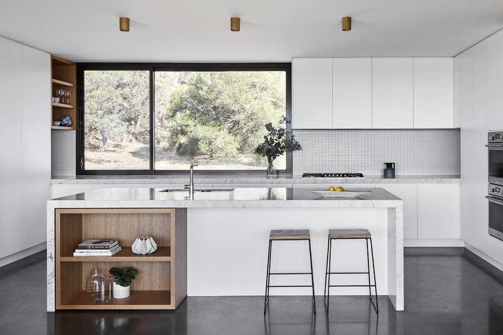 Large contemporary kitchen in Melbourne with marble benchtops, stainless steel appliances, concrete floors, with island, grey floor, grey benchtop, a double-bowl sink, flat-panel cabinets, white cabinets and grey splashback.