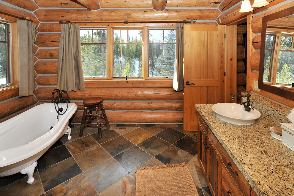 Claw-foot bathtub - large rustic master multicolored tile and stone tile slate floor claw-foot bathtub idea with a vessel sink, shaker cabinets, distressed cabinets, granite countertops and a two-piece toilet