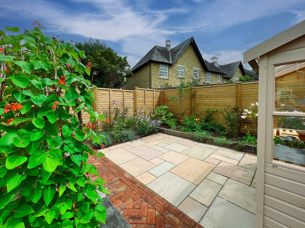 Idées déco pour un jardin arrière victorien de taille moyenne et l'été avec une exposition partiellement ombragée, des pavés en pierre naturelle et une clôture en bois.