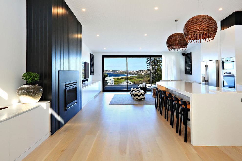 Inspiration for a large contemporary galley open plan kitchen in Sydney with flat-panel cabinets, white cabinets, stainless steel appliances, light hardwood floors, with island, a drop-in sink and quartz benchtops.