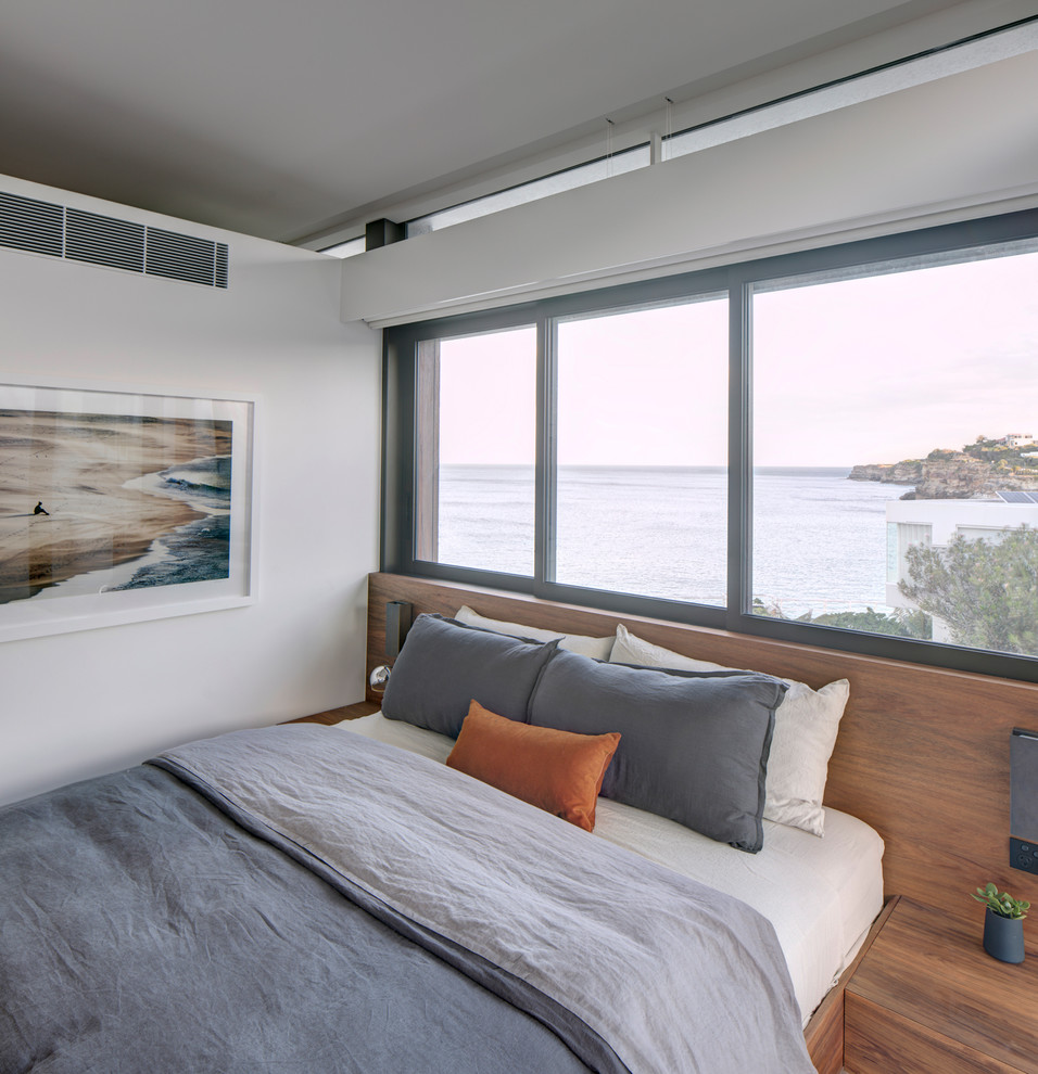 Photo of a mid-sized contemporary master bedroom in Sydney with white walls and medium hardwood floors.