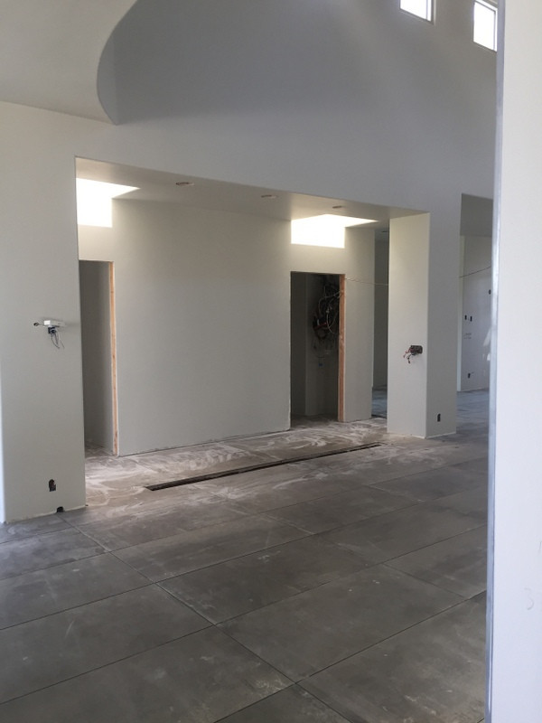 Immagine di un'ampia sala da pranzo aperta verso il soggiorno minimalista con pareti bianche, pavimento in gres porcellanato, pavimento grigio e travi a vista