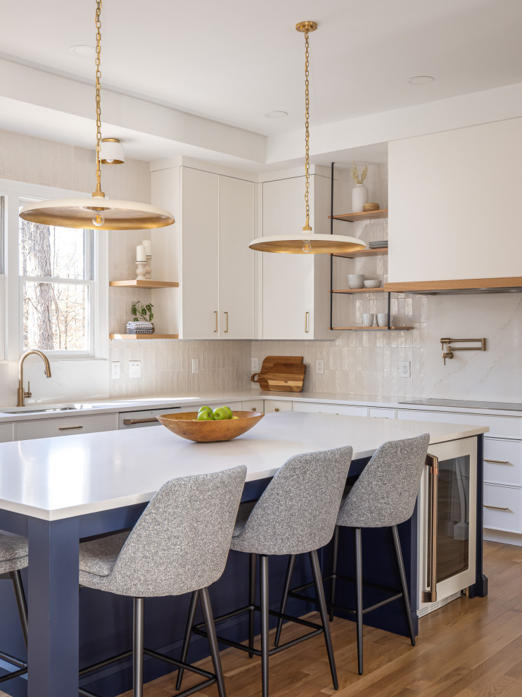 Design ideas for a transitional open plan kitchen in Raleigh with an undermount sink, white cabinets, quartzite benchtops, white splashback, porcelain splashback, white appliances, medium hardwood floors, with island, brown floor, white benchtop and recessed.