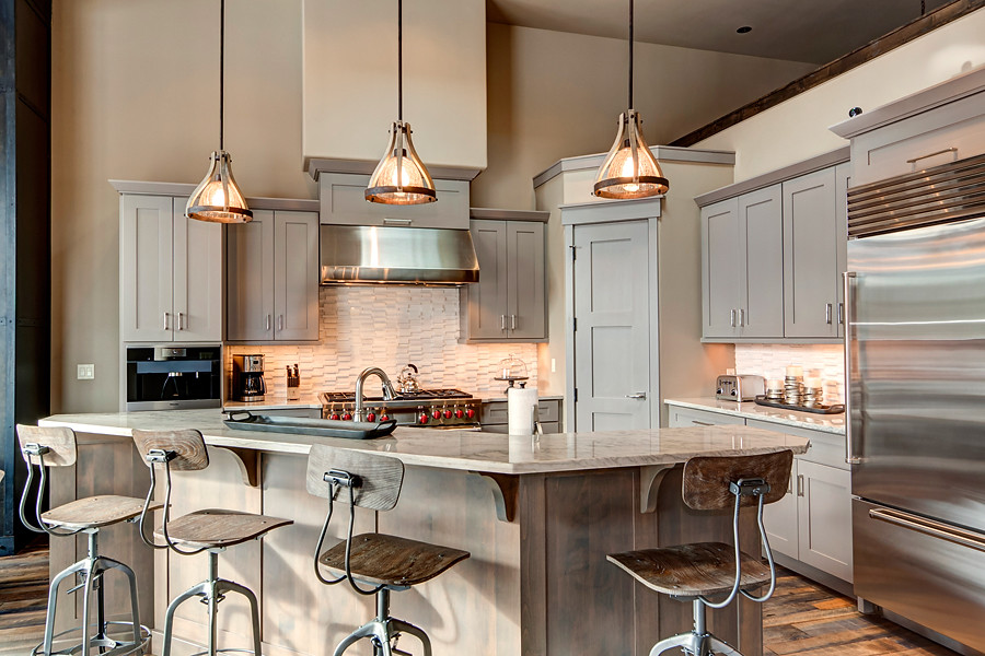 Inspiration for a transitional u-shaped medium tone wood floor eat-in kitchen remodel in Denver with a farmhouse sink, recessed-panel cabinets, gray cabinets, marble countertops, white backsplash, ceramic backsplash, stainless steel appliances and an island