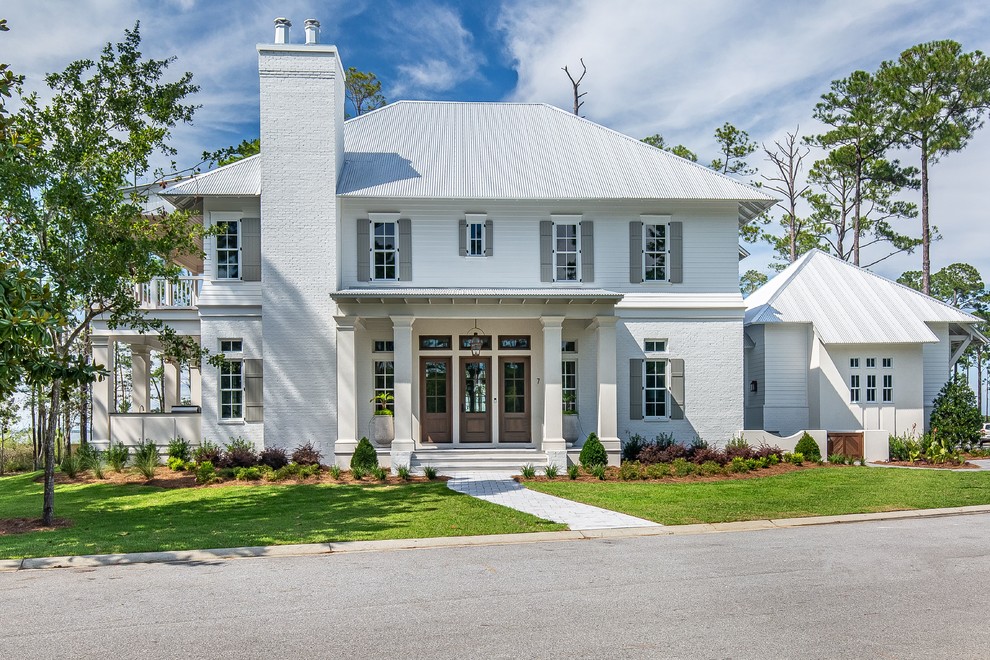 Large country two-storey brick white house exterior in New Orleans with a gable roof and a metal roof.