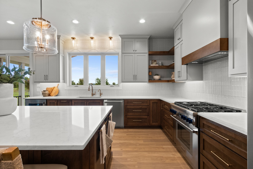 Example of a large transitional l-shaped vinyl floor and brown floor eat-in kitchen design with an undermount sink, shaker cabinets, brown cabinets, quartz countertops, white backsplash, porcelain backsplash, stainless steel appliances, an island and white countertops