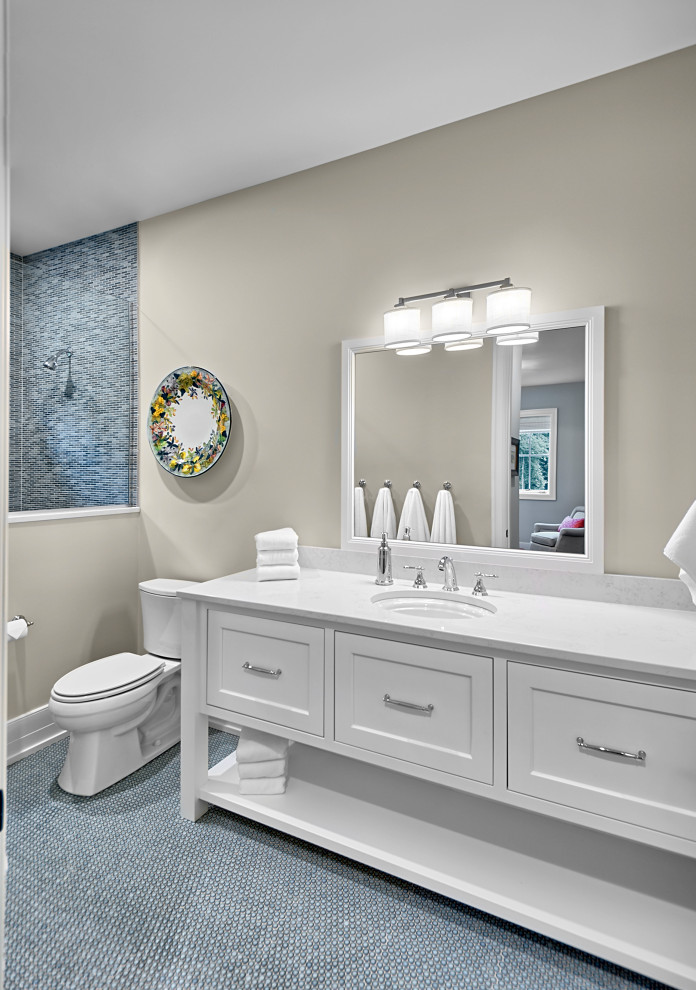 Photo of a mid-sized transitional bathroom in Grand Rapids with shaker cabinets, white cabinets, a curbless shower, a two-piece toilet, blue tile, ceramic tile, beige walls, ceramic floors, an undermount sink, engineered quartz benchtops, blue floor, a hinged shower door, white benchtops, a shower seat, a single vanity and a built-in vanity.