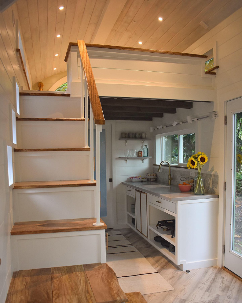 Photo of a mid-sized beach style galley eat-in kitchen in Hawaii with an undermount sink, flat-panel cabinets, white cabinets, quartz benchtops, grey splashback, ceramic splashback, white appliances, vinyl floors, no island, grey floor, grey benchtop and timber.