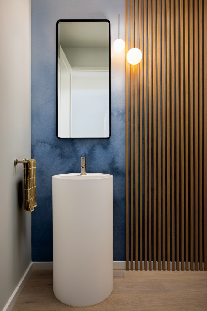 Powder room - contemporary light wood floor, beige floor, wallpaper and wood wall powder room idea in San Francisco with white cabinets, blue walls, a vessel sink and a freestanding vanity