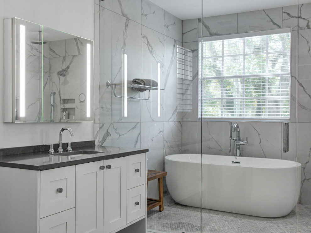 Inspiration for a large contemporary master wet room bathroom in Tampa with recessed-panel cabinets, white cabinets, a freestanding tub, white tile, porcelain tile, white walls, porcelain floors, an undermount sink, engineered quartz benchtops, grey floor, a hinged shower door, grey benchtops, a single vanity and a built-in vanity.