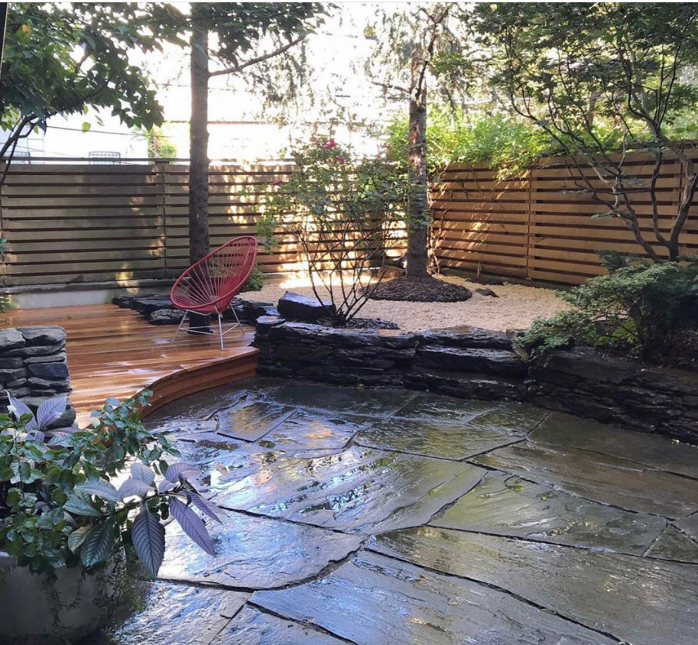 This is an example of a mid-sized transitional backyard shaded garden in New York with natural stone pavers.