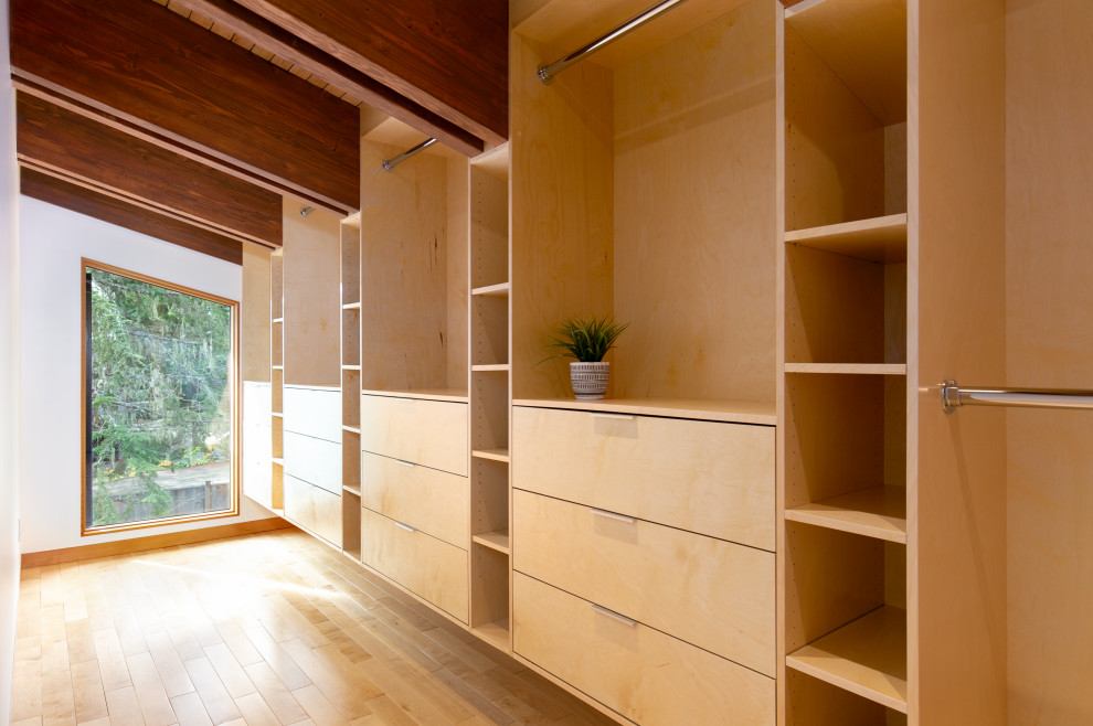 Expansive contemporary gender-neutral walk-in wardrobe in Other with flat-panel cabinets, medium wood cabinets and vaulted.