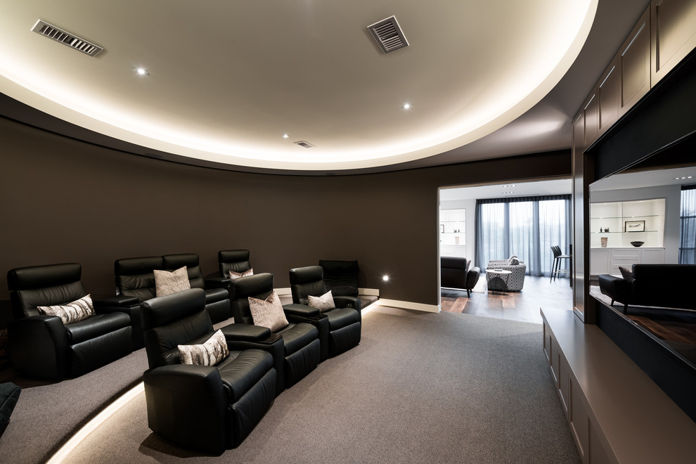 Photo of a contemporary enclosed home theatre in Melbourne with brown walls, carpet, a wall-mounted tv and grey floor.