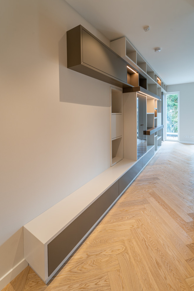 Immagine di un soggiorno minimalista di medie dimensioni e aperto con libreria e parquet chiaro