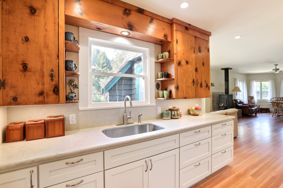 This is an example of a small eclectic galley eat-in kitchen in San Francisco with an undermount sink, shaker cabinets, white cabinets, wood benchtops, green splashback, subway tile splashback, stainless steel appliances and light hardwood floors.