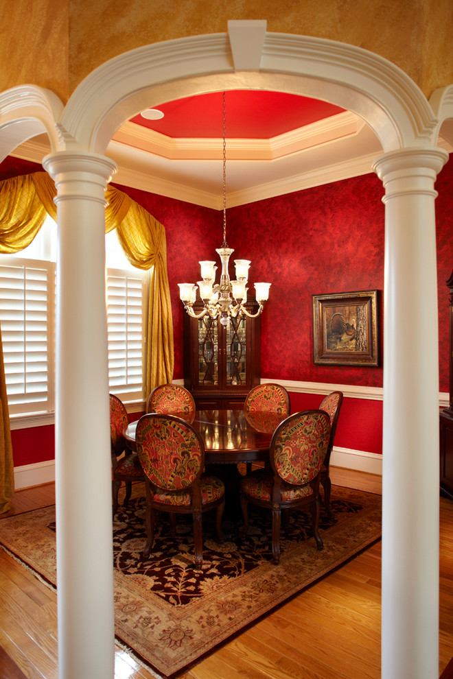 Enclosed dining room - mid-sized transitional medium tone wood floor enclosed dining room idea with red walls