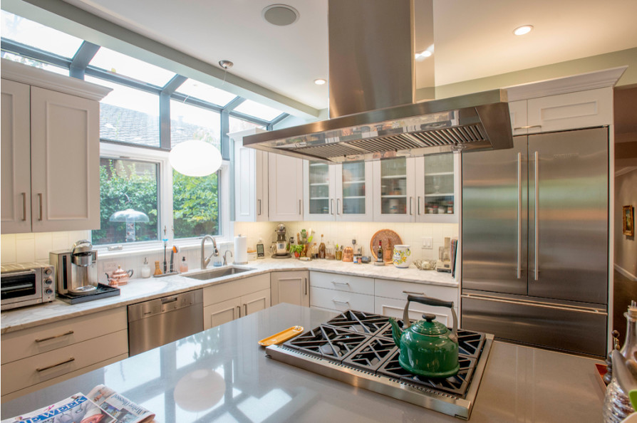 Kitchen - mid-sized transitional l-shaped kitchen idea in Denver with an undermount sink, glass-front cabinets, white cabinets, quartzite countertops, white backsplash, ceramic backsplash, stainless steel appliances and an island