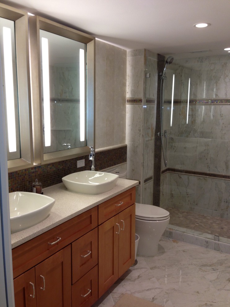 Photo of a transitional 3/4 bathroom in Tampa with recessed-panel cabinets, medium wood cabinets, an alcove shower, a one-piece toilet, gray tile, slate, grey walls, marble floors, a vessel sink, engineered quartz benchtops, white floor and a hinged shower door.