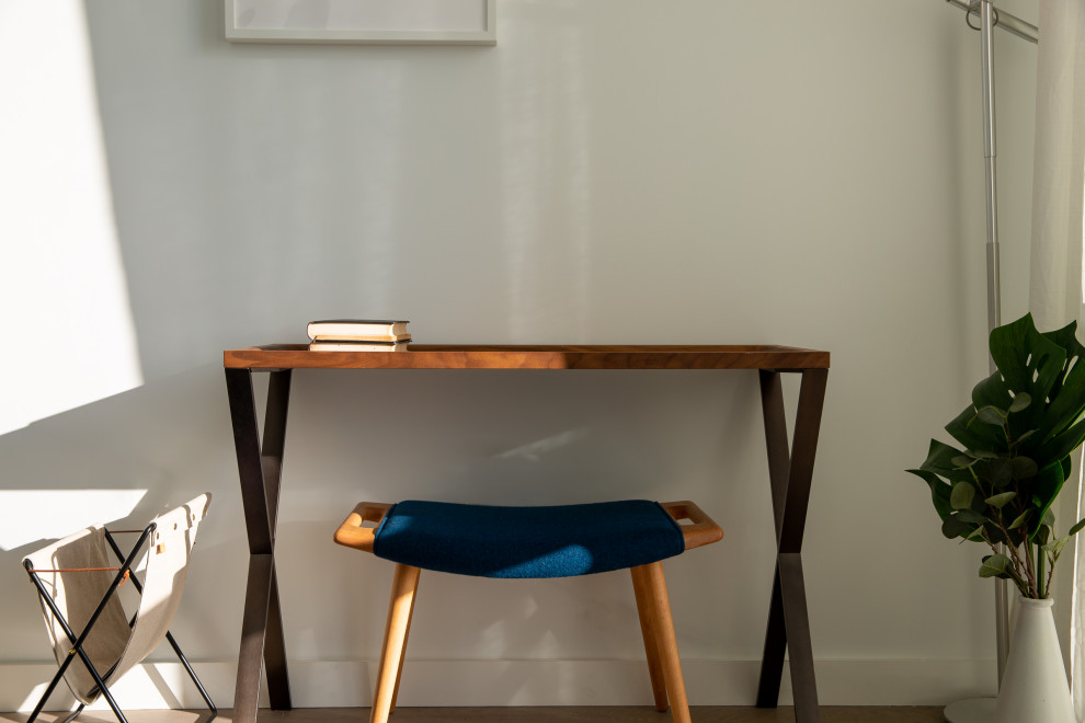 Ejemplo de despacho actual pequeño con paredes blancas, suelo de madera clara, escritorio independiente y suelo marrón