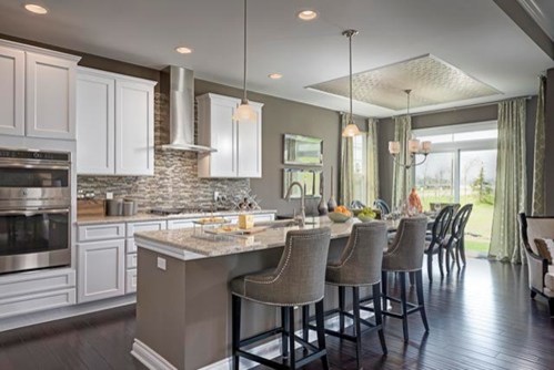 Mid-sized transitional single-wall dark wood floor eat-in kitchen photo in Chicago with shaker cabinets, mosaic tile backsplash, stainless steel appliances, an island, an undermount sink, white cabinets, granite countertops and multicolored backsplash