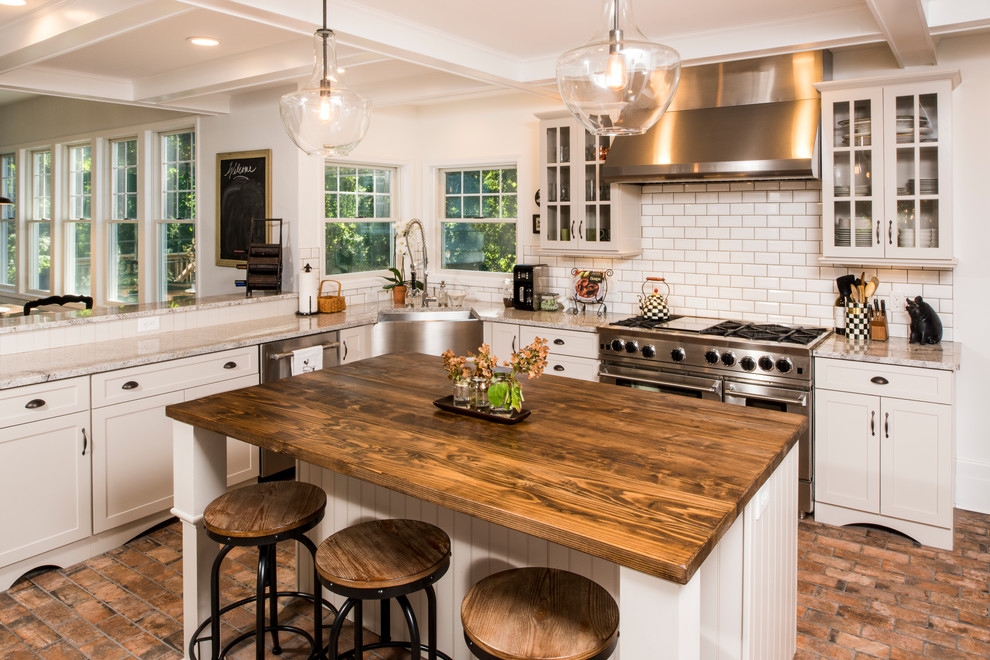 Photo of a large country l-shaped eat-in kitchen in New York with a farmhouse sink, shaker cabinets, white cabinets, granite benchtops, white splashback, subway tile splashback, stainless steel appliances, terra-cotta floors and with island.