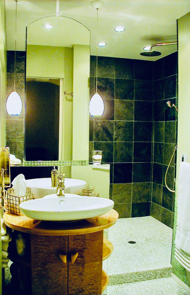 This is an example of a medium sized contemporary ensuite wet room bathroom in Other with freestanding cabinets, light wood cabinets, a built-in bath, a wall mounted toilet, green tiles, slate tiles, green walls, pebble tile flooring, a vessel sink, wooden worktops, white floors, an open shower, a wall niche, a single sink and a freestanding vanity unit.