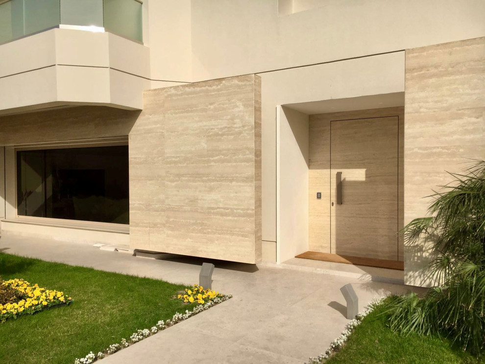 Immagine di una porta d'ingresso minimal con pareti beige, pavimento in pietra calcarea, una porta singola e pavimento beige