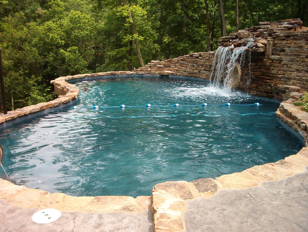 Inspiration for a large country backyard custom-shaped natural pool in Other with a water feature and stamped concrete.