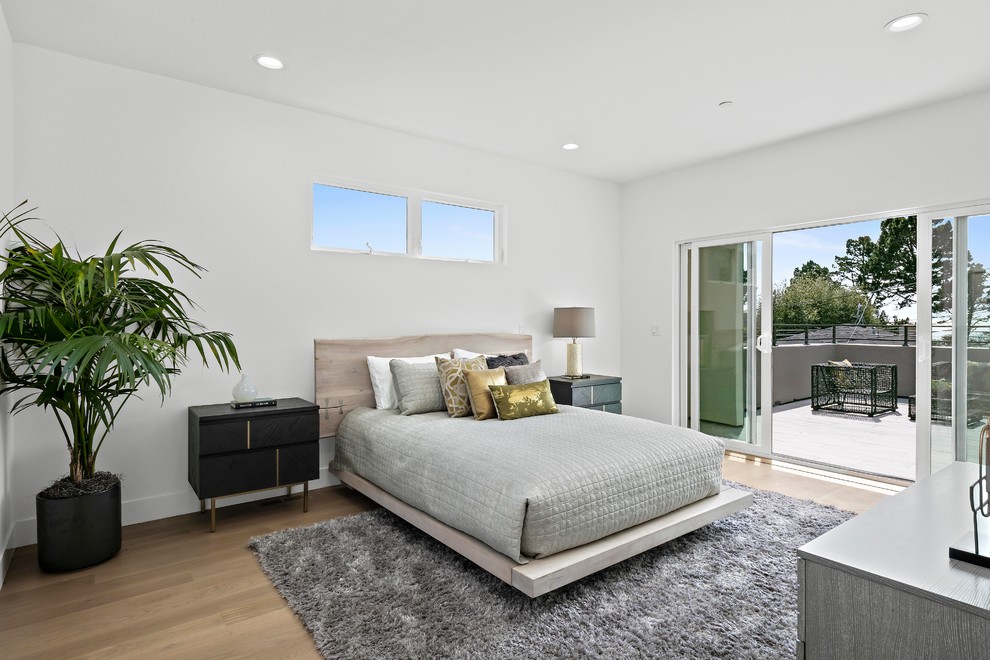 This is an example of a contemporary bedroom in San Francisco with white walls, light hardwood floors, no fireplace and beige floor.