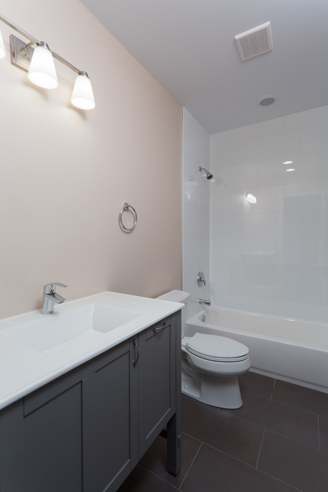 Inspiration for a mid-sized contemporary master bathroom in Chicago with flat-panel cabinets, grey cabinets, a corner tub, a shower/bathtub combo, a one-piece toilet, white tile, multi-coloured walls, painted wood floors, an undermount sink, engineered quartz benchtops, brown floor and a sliding shower screen.
