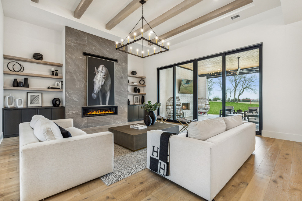 Photo of a large contemporary open concept living room in Dallas with white walls, light hardwood floors, a ribbon fireplace, a tile fireplace surround, no tv, white floor and exposed beam.