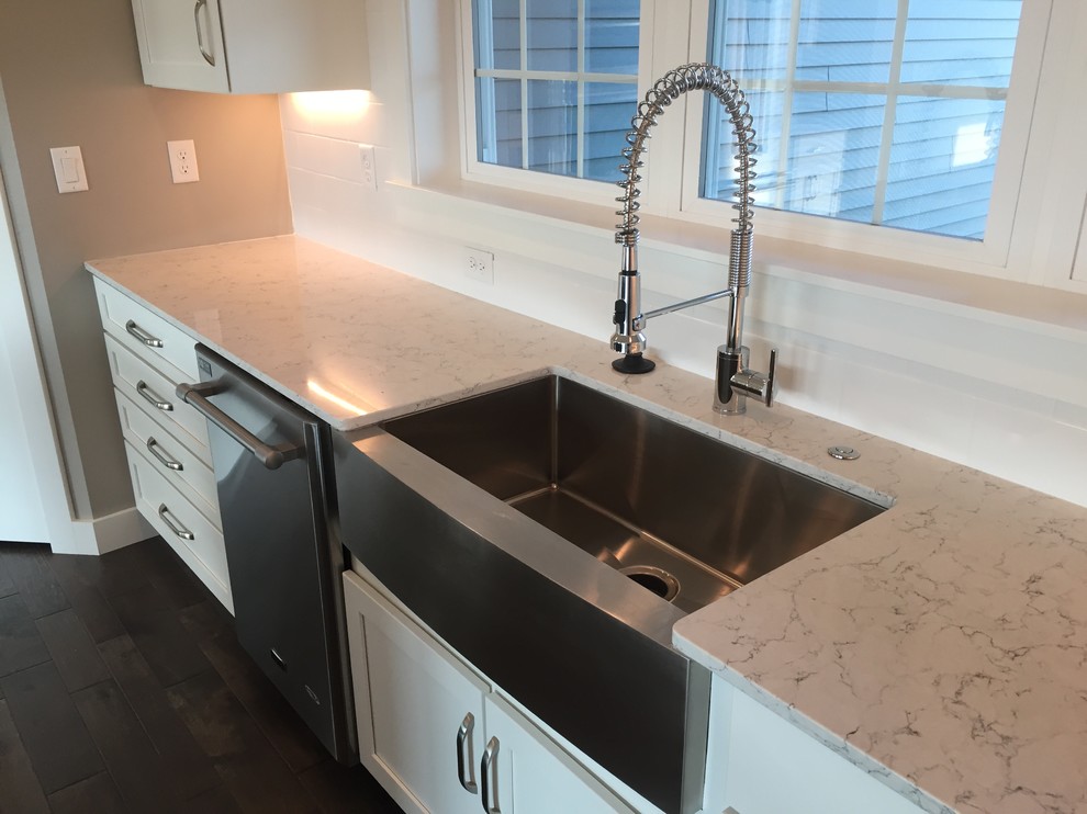 Kitchen - mid-sized transitional l-shaped dark wood floor and brown floor kitchen idea with a farmhouse sink, shaker cabinets, white cabinets, quartz countertops, white backsplash, ceramic backsplash, stainless steel appliances, an island and white countertops