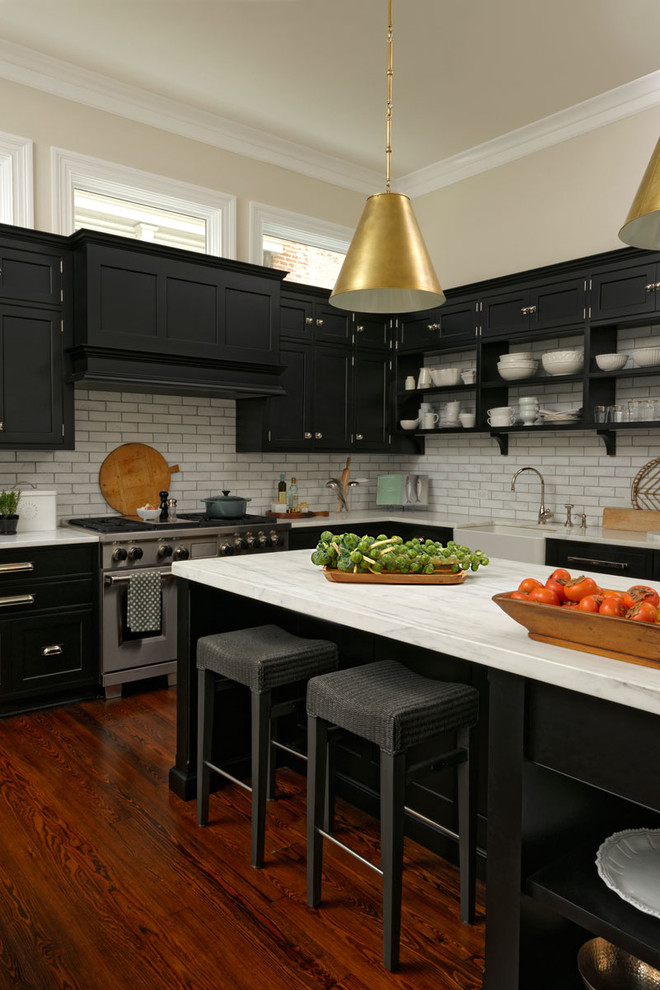 Large transitional l-shaped medium tone wood floor and brown floor eat-in kitchen photo in DC Metro with a farmhouse sink, beaded inset cabinets, black cabinets, white backsplash, subway tile backsplash, stainless steel appliances, an island and quartzite countertops