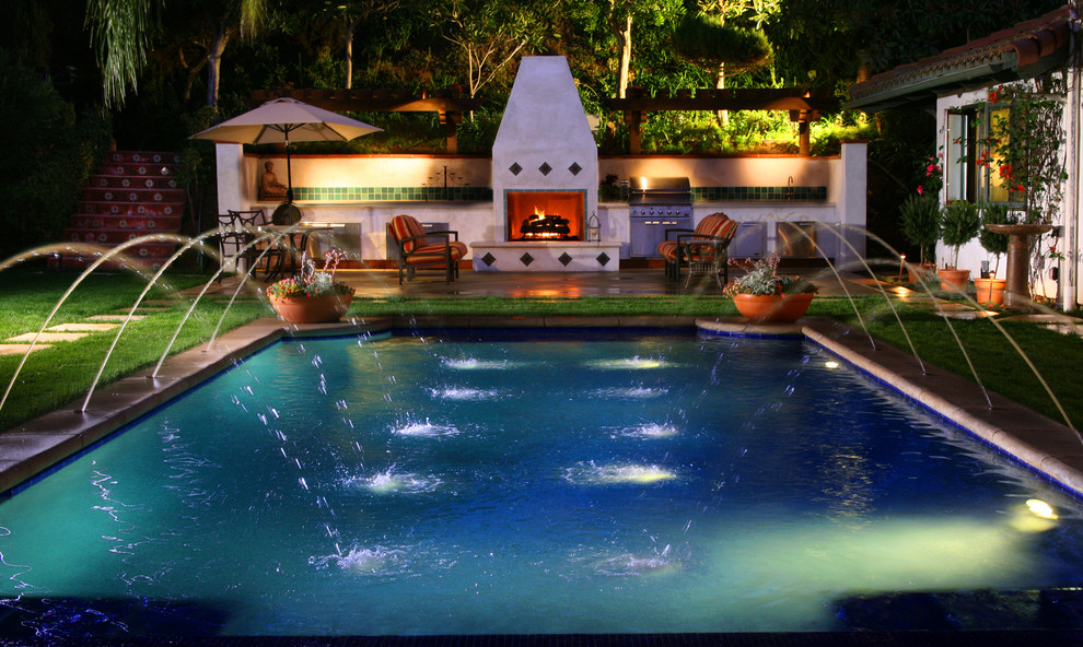 This is an example of a mid-sized mediterranean backyard custom-shaped lap pool in Los Angeles with a water feature.