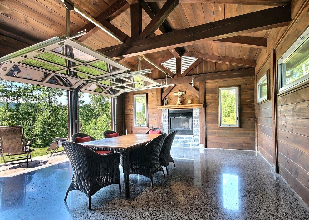 Photo of a large country separate dining room in Montreal with concrete floors, a standard fireplace, a tile fireplace surround and grey floor.