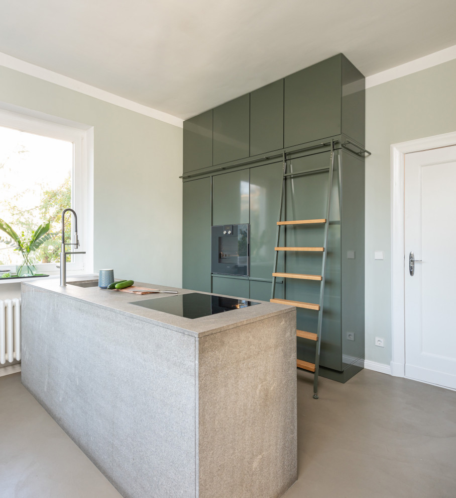Photo of a mid-sized contemporary galley kitchen in Berlin with flat-panel cabinets, green cabinets, grey benchtop, an undermount sink, panelled appliances, a peninsula and grey floor.