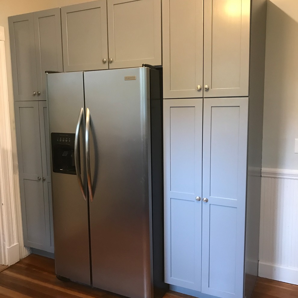 Mid-sized transitional l-shaped medium tone wood floor and brown floor enclosed kitchen photo with an undermount sink, shaker cabinets, gray cabinets, granite countertops, white backsplash, subway tile backsplash, no island and black countertops