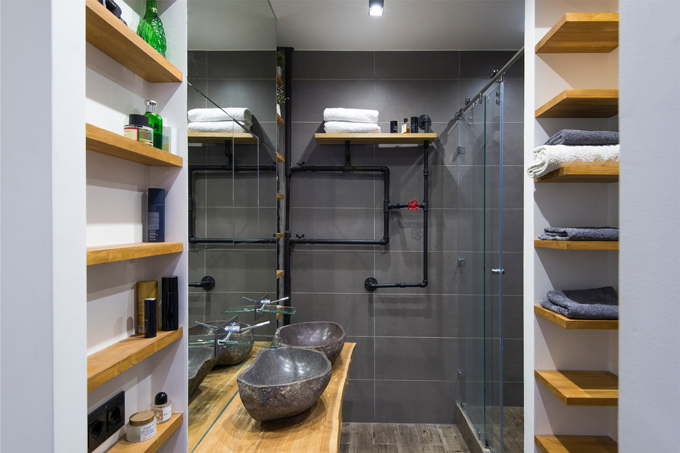 Photo of a mid-sized industrial 3/4 bathroom in Moscow with open cabinets, light wood cabinets, an alcove shower, gray tile, porcelain tile, porcelain floors, a vessel sink, wood benchtops, a sliding shower screen, brown floor and brown benchtops.