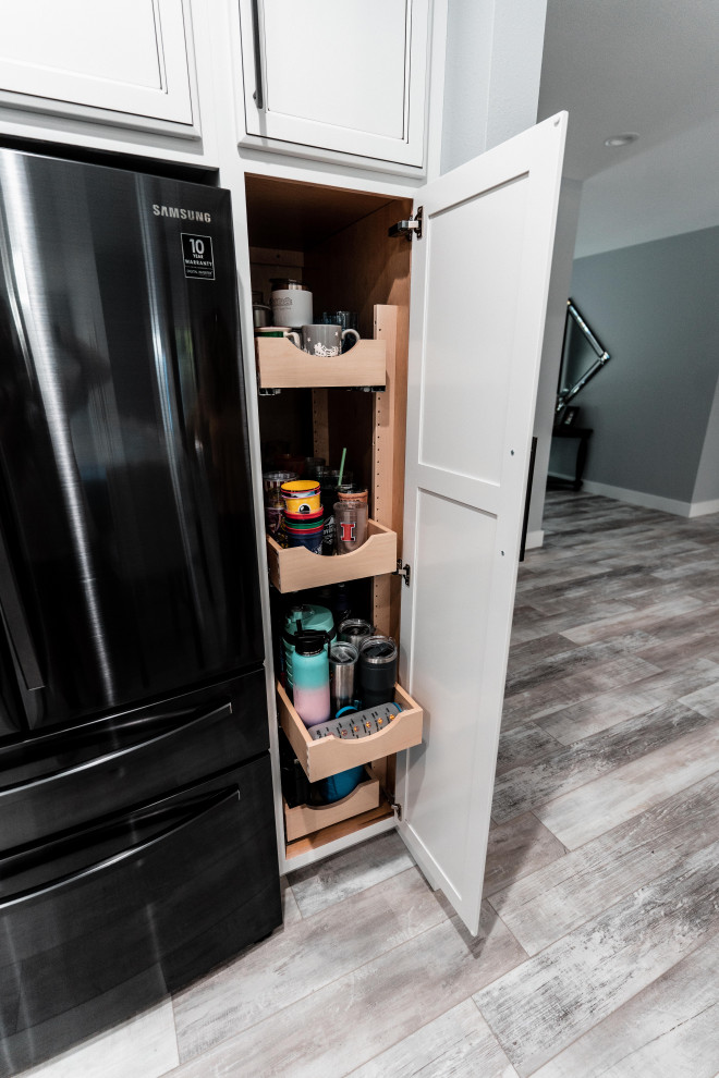 Open concept kitchen - huge transitional l-shaped laminate floor, gray floor and tray ceiling open concept kitchen idea with an undermount sink, flat-panel cabinets, white cabinets, quartz countertops, gray backsplash, ceramic backsplash, black appliances and an island