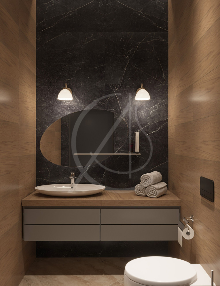Photo of a mid-sized modern master bathroom in London with flat-panel cabinets, light wood cabinets, a wall-mount toilet, black tile, marble, white walls, marble floors, a vessel sink, beige floor and brown benchtops.