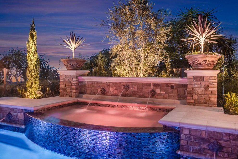 Large transitional backyard custom-shaped pool in Orange County with a hot tub and natural stone pavers.