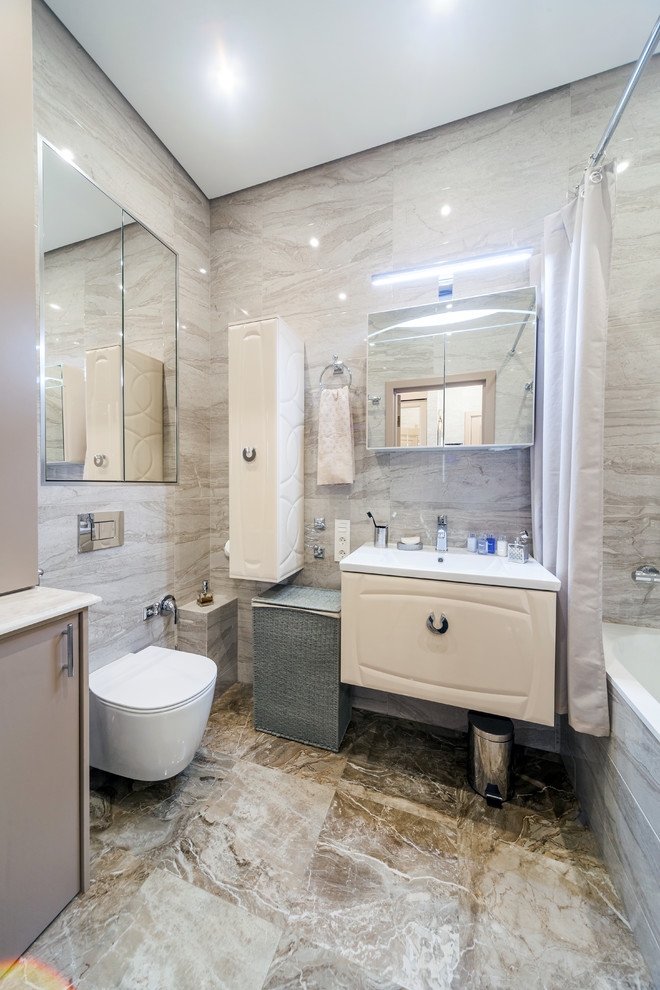 Photo of a small transitional master bathroom in Saint Petersburg with raised-panel cabinets, beige cabinets, an undermount tub, a shower/bathtub combo, a wall-mount toilet, beige tile, ceramic tile, beige walls, porcelain floors, a drop-in sink, beige floor and a shower curtain.